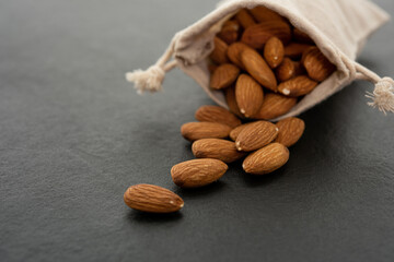 Sack with almond on black background.  (selective focus; close-up shot)