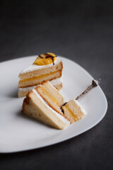 cake on a dessert plate. brownie with white cream on a dark background. cake close-up. cut cake.