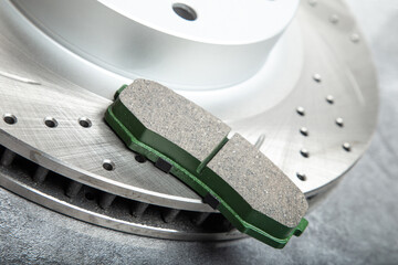 brake pads and perforated brake discs on a stone gray table