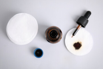 Bottle of medical iodine, dropper and cotton pads on grey background, flat lay