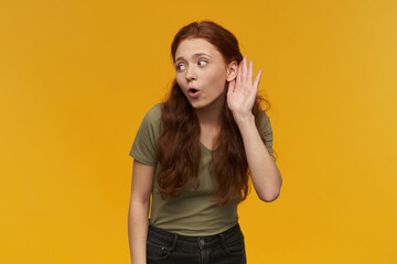 Portrait of curious, beautiful lady with long ginger hair. Wearing green t-shirt. People and...