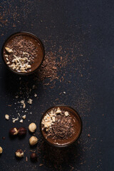 Homemade dark chocolate mousse with hazelnut in glasses on dark grey table