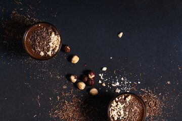 Homemade dark chocolate mousse with hazelnut in glasses on dark grey table