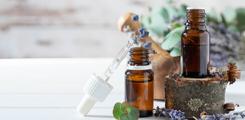 organic cosmetics concept, glass bottle with oil, pipette and lavander flowers, eucaliptus on light...