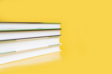 A stack of books on a yellow background. The books are on a plain background with space for...