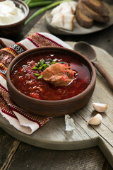 Borscht - Traditional Ukrainian dish.  Vegetable soup made from beets, potatoes, cereals and boiled meat, and  slices of rye bread in a ceramic bowl on a wooden kitchen table. Russian  food cuisine
