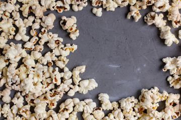 Frame of fresh popcorn on grey stone background. Top view