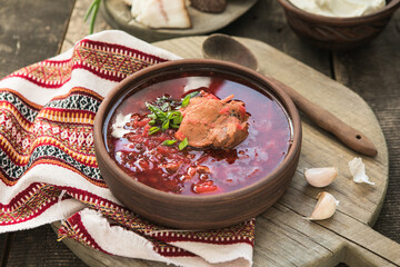 Borscht - Traditional Ukrainian dish.  Vegetable soup made from beets, potatoes, cereals and boiled meat, and  slices of rye bread in a ceramic bowl on a wooden kitchen table. Russian  food cuisine