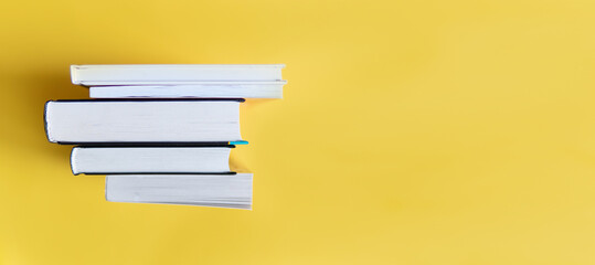 A stack of books on a yellow background. The books are on a plain background with space for...