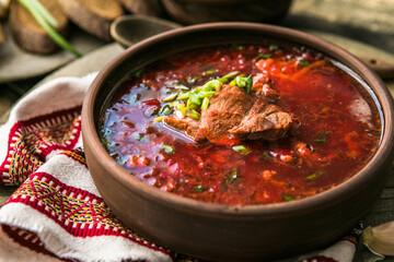 Borscht - Traditional Ukrainian dish.  Vegetable soup made from beets, potatoes, cereals and boiled meat, and  slices of rye bread in a ceramic bowl on a wooden kitchen table. Russian  food cuisine