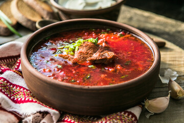 Borscht - Traditional Ukrainian dish.  Vegetable soup made from beets, potatoes, cereals and boiled meat, and  slices of rye bread in a ceramic bowl on a wooden kitchen table. Russian  food cuisine