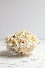 popcorn in a transparent glass bowl on white table