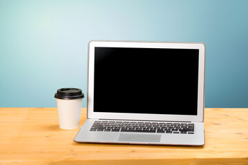 Fototapeta na wymiar Mockup blank laptop screen with coffee on wooden table in coworking space.