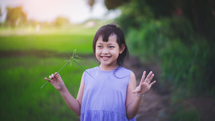 Happy asian little girl smiling at the green field