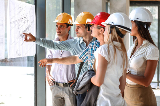 Architects and engineers looking and  discuss with construction manager about blueprint of construction project.