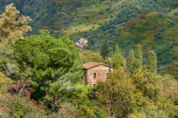 Fototapeta na wymiar an abandoned house in the mountains of Eastern Sicily with spring vegetation and other distant houses among the reliefs