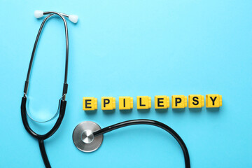 Word Epilepsy and stethoscope on light blue background, flat lay. Space for text