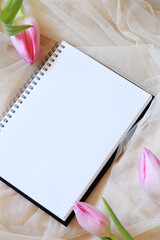 empty notebook with spiral and pink tulip flowers on tulle fabric
