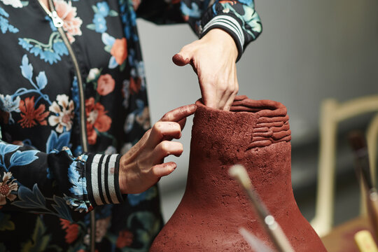 Closeup shot of hands sculpting a clay vase