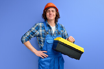 confident curly caucasian male with tools box for repair isolated on purple background