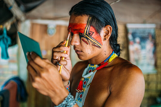 Indian from the Pataxó tribe, using a mirror and doing face painting.