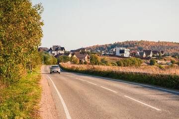 Drive along the autumn highway of the country road among the beautiful autumn hills with cottages. A sharp turn on the road