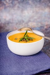 Homemade orange pumpkin diet soup puree with pumpkin seeds and rosemary