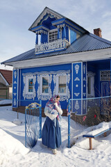 Russian girl in Pavlovo Posad shawl. Wooden rural house with carved windows in Purekh village,...