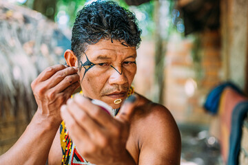 Indian from the Pataxó tribe, using a mirror and doing face painting.