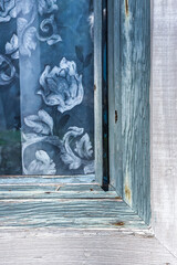 Blue curtain hanging in weathered wooden window
