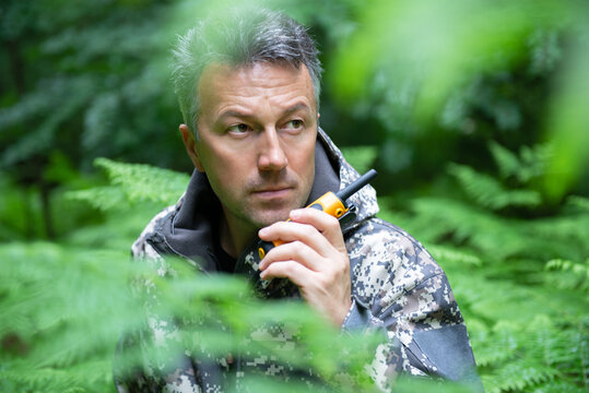 Mature man walking and hiking in mountain forest and using radio set. Male spring outdoor portrait.