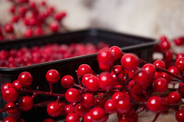 Frozen winter berries with ice in a bowl on the table branches and leaves food blurred background