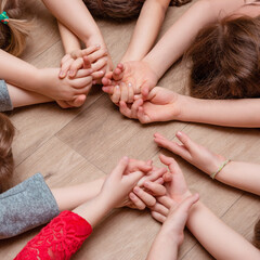 Children's hands reaching out to the middle forming a circle