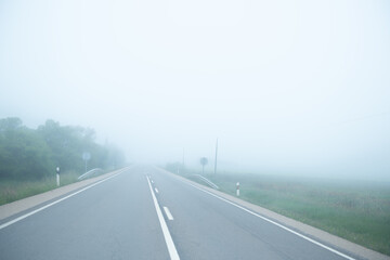 Mysterious road with nobody at spring foggy weather