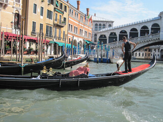 Fototapeta na wymiar Venice old city grand canal with gondolas and boats. Romantic swimming in the morning. Comfotrable transportation to ancient historic hotel. Scenic Venetian scape on a sunny day.