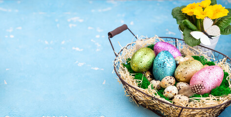 Spring Easter background for holiday. Easter composition with colorful Easter eggs on moss in basket and spring flower. Happy Easter concept. Copy space