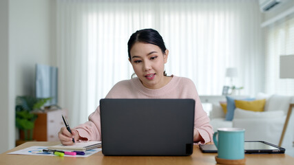 Young attractive business asian woman talking about sale report in video call conference on notebook computer online meeting in working from home, Working remotely and Social isolation concept.