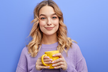 young caucasian teen girl in casual wear holding yellow cup of coffee or tea in hands,isolated