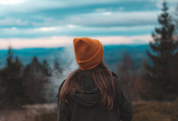 Blonde woman in a cap relaxes at sunset in the Beskid Mountains.