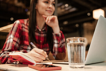 blurred freelancer holding pen near notebook and gadgets on table