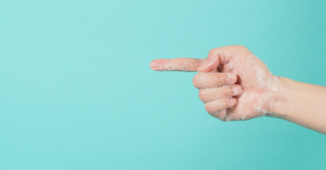 Hand is pointing and have foam soap bubbles on a green mint or Tiffany Blue isolated background