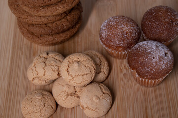 muffins, almond amaretti and oat cookies on wooden stand board. sweet bakery concept