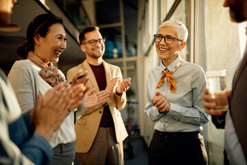 Group of happy business people applauding to their female executive manager in the office. - obrazy, fototapety, plakaty