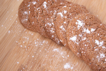 oatmeal cookies covered in powdered sugar on wooden stand board. sweet bakery concept