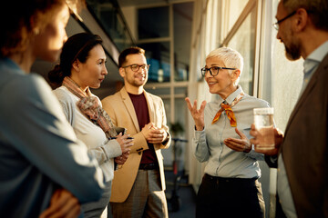 Mature businesswoman talking to group of co-workers while holding staff meeting in the office.