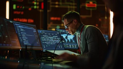 Professional IT Technical Support Specialist Making an Intercom Announcement on a Microphone and Working on Desktop Computer in Monitoring Control Room with Big Digital Screens with Server Data.