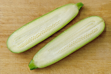 raw zucchini halfs on a wooden cutting board