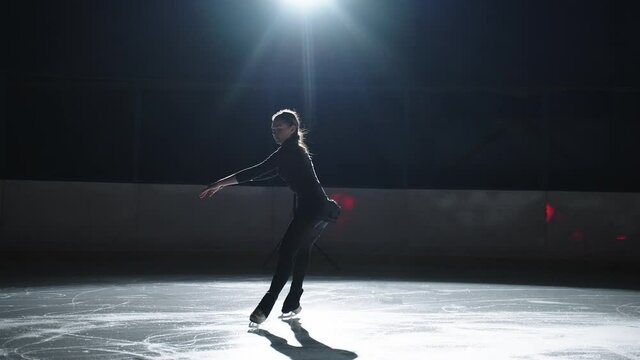 young athletic woman is skating on ice rink, training elements of figure skating, professional sportswoman