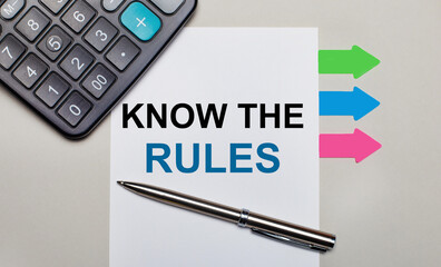 On a light gray background, a calculator, a white sheet with the text KNOW THE RULES, a pen and...
