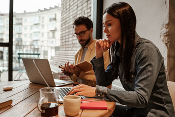 brunette freelancer using laptop near man in cafe